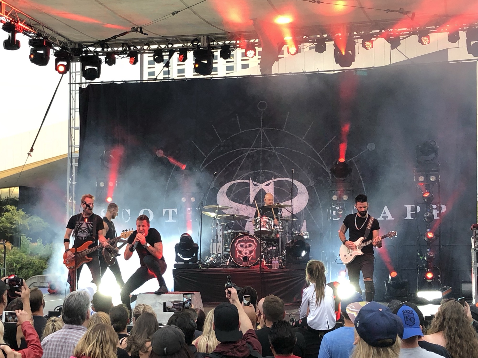 A rock band performing under stage lights to a crowd at Pig Out in the Park.